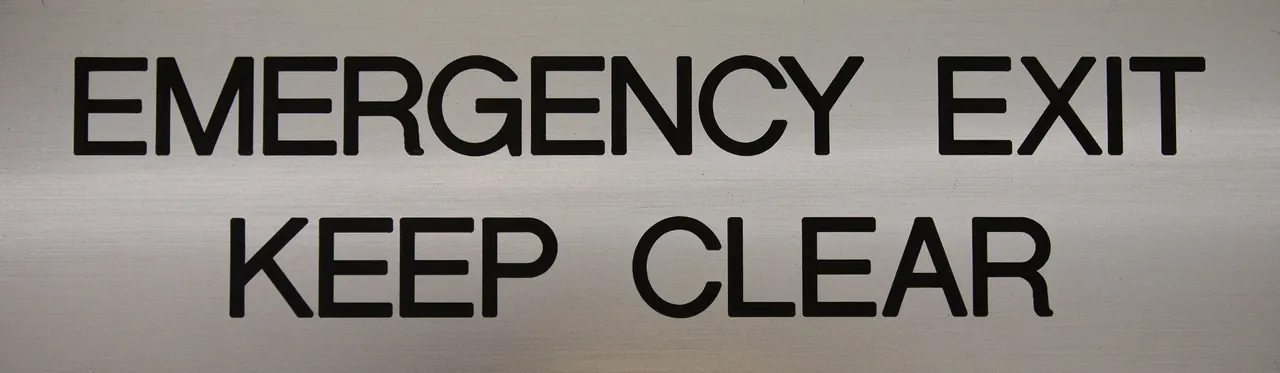 Brushed aluminium sign reading emergency exit keep clear