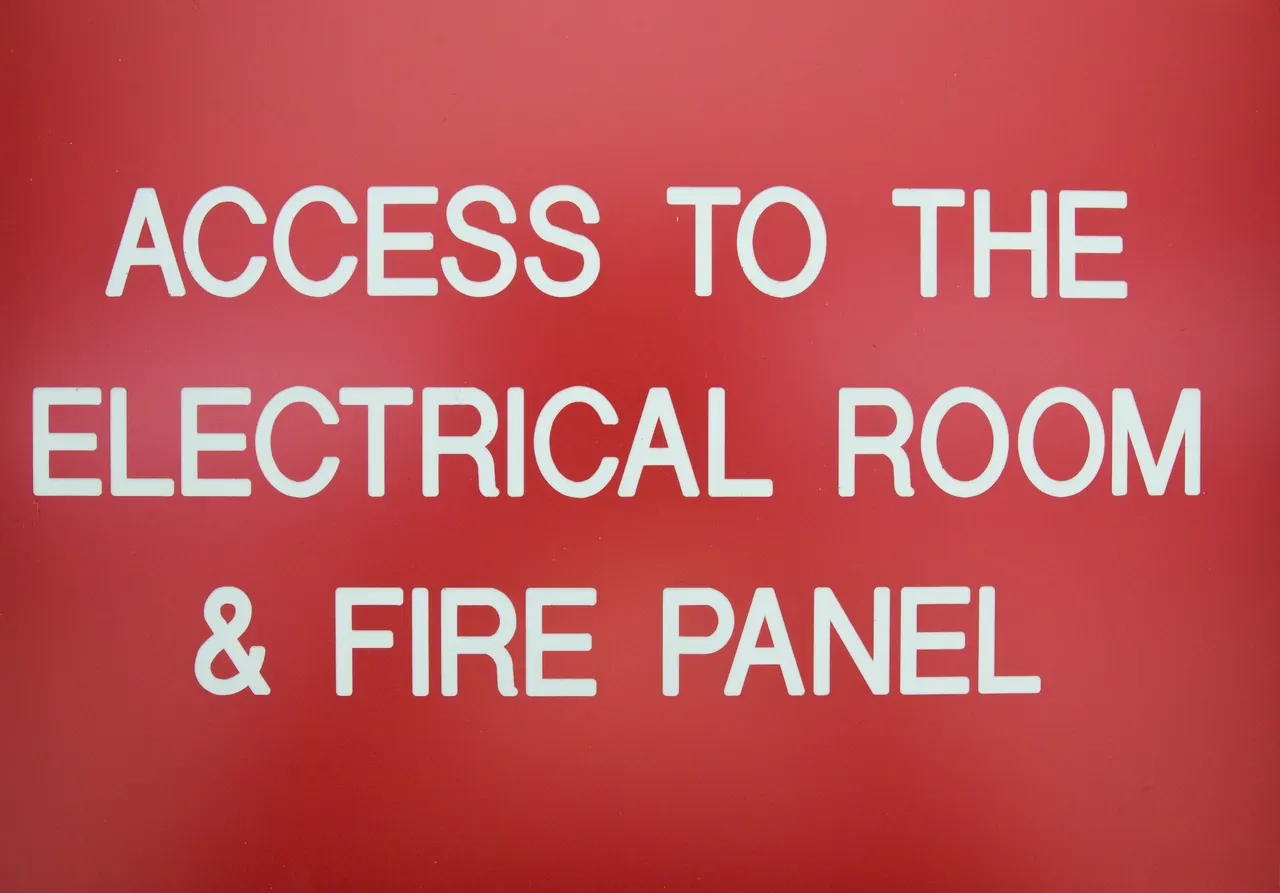Red engraved sign reading access to the electrical room and fire panel