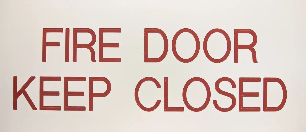 White engraved sign reading fire door keep closed