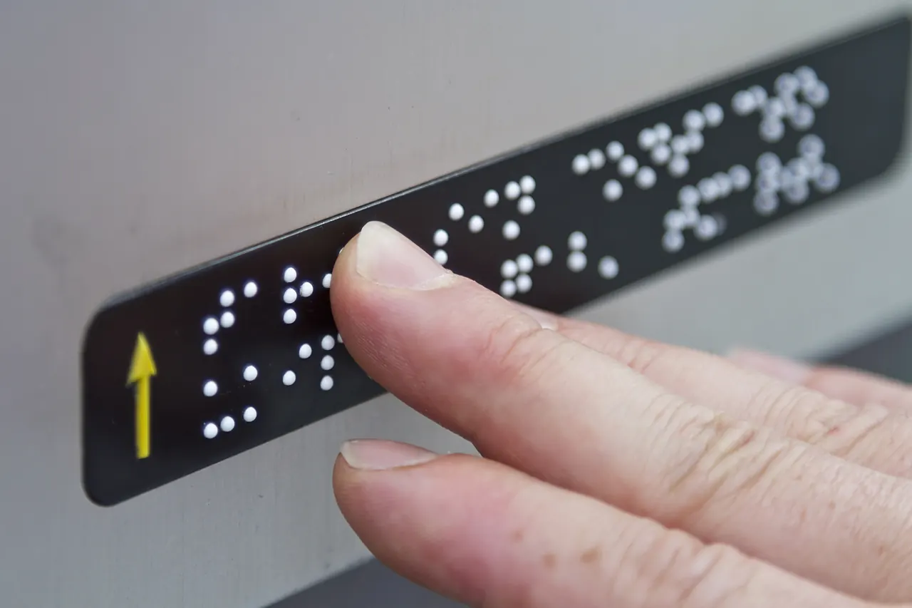 Finger reading braille on a tactile sign